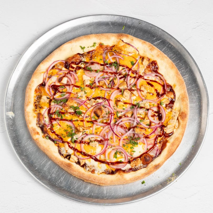 St. Lucie West Pizzeria's BBQ chicken pizza with red onions and cilantro on a metal tray.